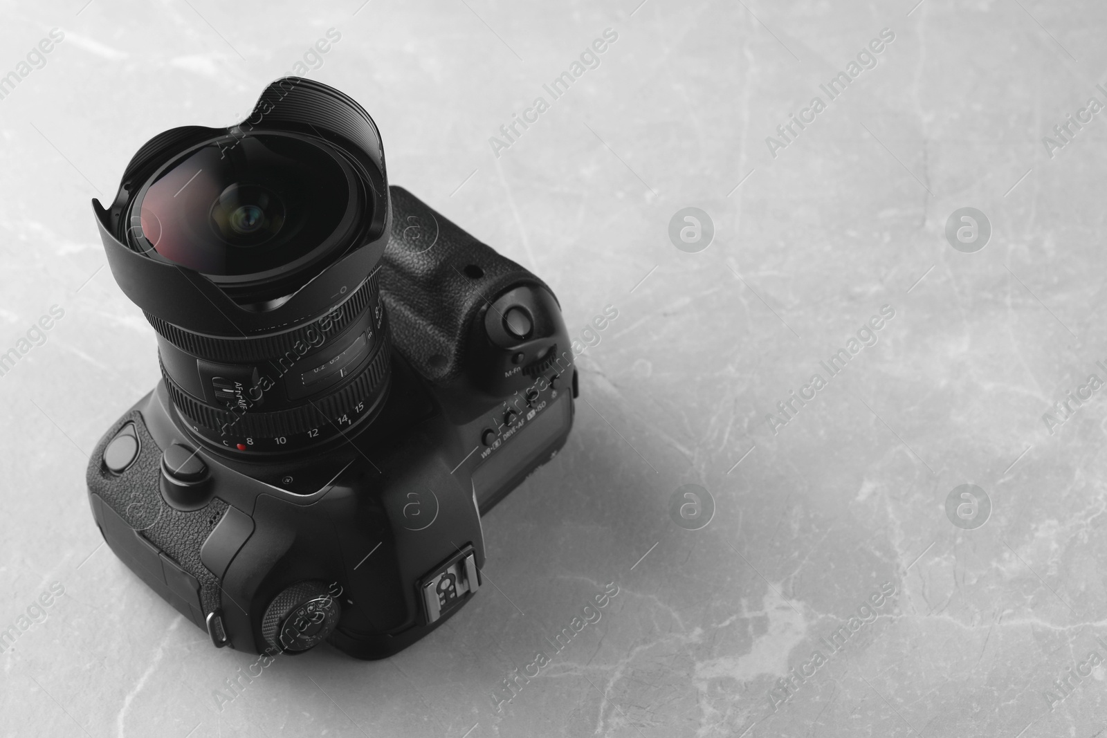 Photo of Modern photo camera on light grey marble table, space for text