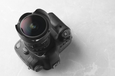 Photo of Modern photo camera on light grey marble table, space for text