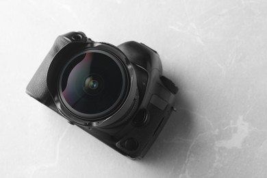 Photo of Modern photo camera on light grey marble table, above view. Space for text