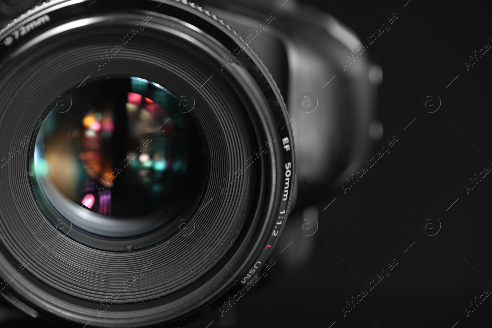 Photo of One modern photo camera on black background, closeup. Space for text