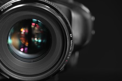 One modern photo camera on black background, closeup. Space for text