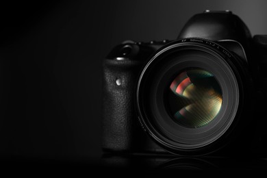 One modern photo camera on black background, space for text