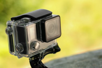 Photo of Modern action camera with mount outdoors, closeup. Space for text