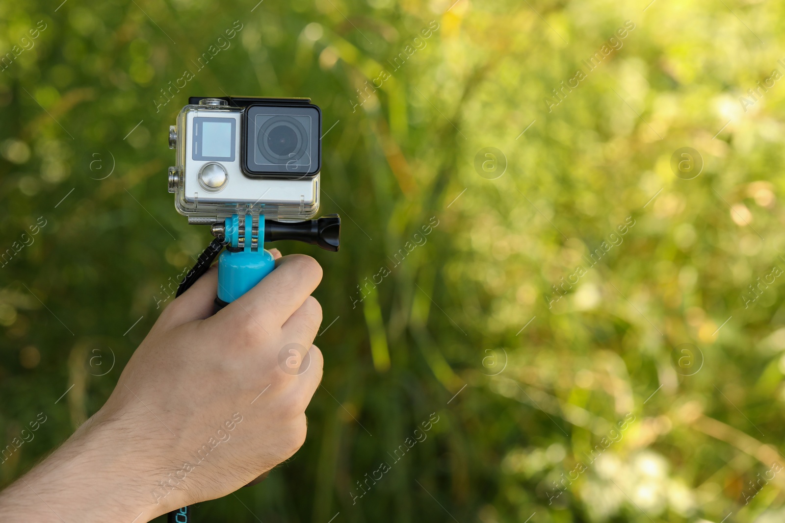 Photo of Man holding monopod with modern action camera outdoors, closeup. Space for text