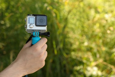 Man holding monopod with modern action camera outdoors, closeup. Space for text