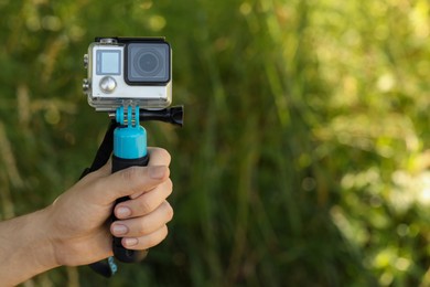 Photo of Man holding monopod with modern action camera outdoors, closeup. Space for text