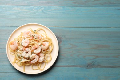 Photo of Delicious pasta with shrimps on blue wooden table, top view. Space for text