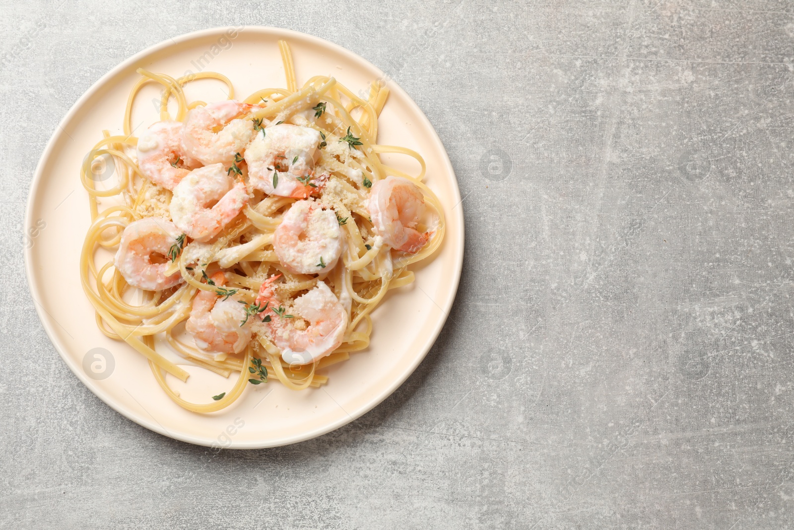 Photo of Delicious pasta with shrimps on grey table, top view. Space for text