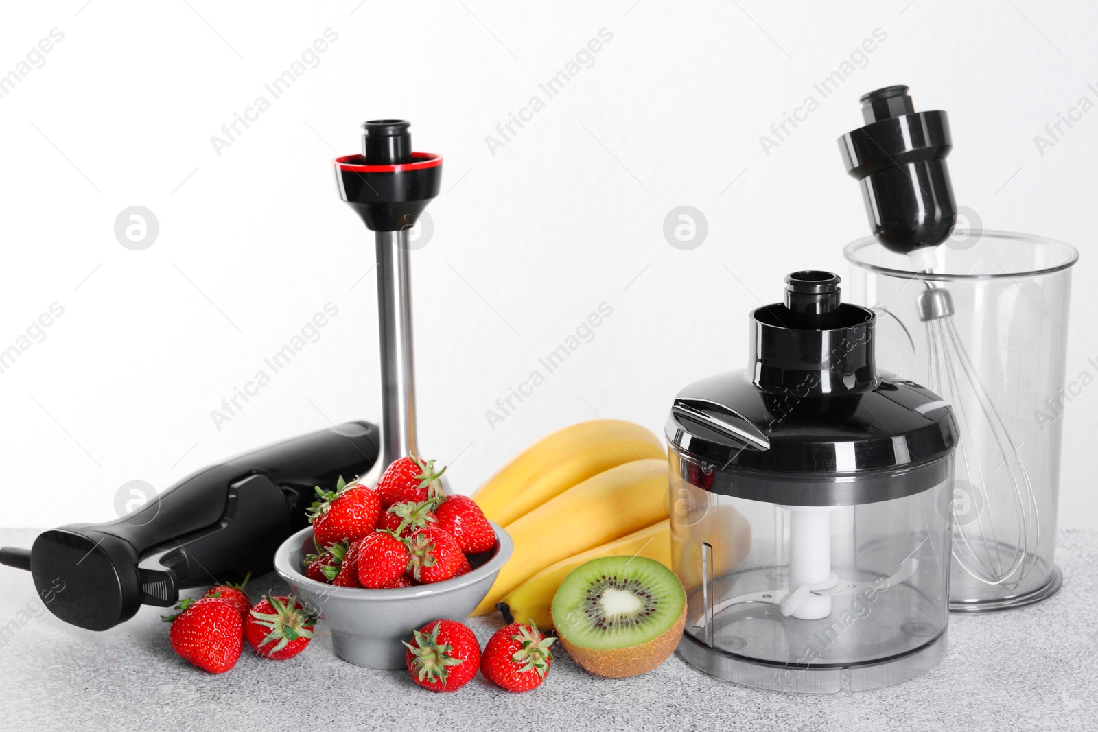 Photo of Hand blender kit, fresh fruits and strawberries on gray table against white background