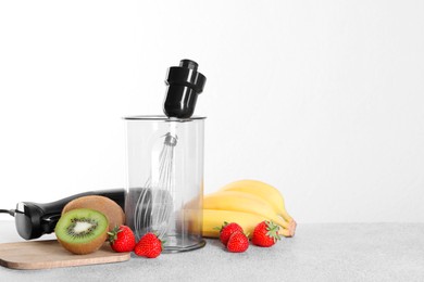 Photo of Hand blender kit, fresh fruits and strawberries on gray table against white background, space for text