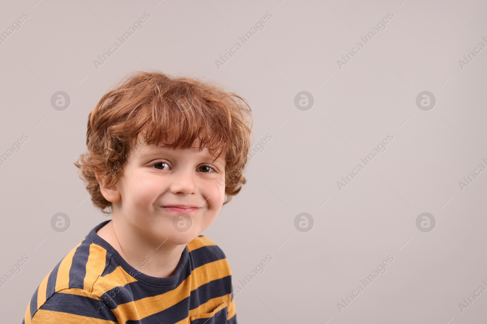 Photo of Portrait of cute little boy on grey background, space for text