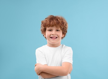 Photo of Portrait of cute little boy on light blue background