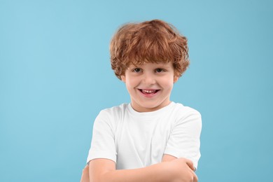 Photo of Portrait of cute little boy on light blue background
