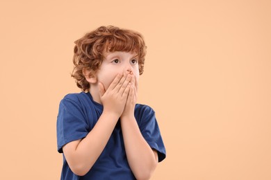 Photo of Portrait of emotional little boy on beige background, space for text