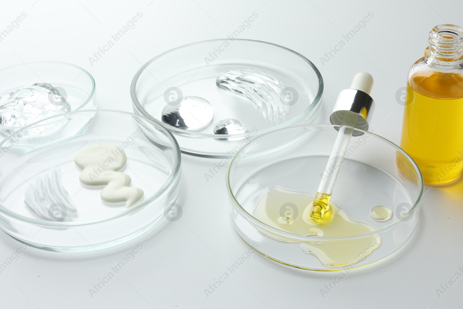 Photo of Petri dishes with different cosmetic products on white background, closeup