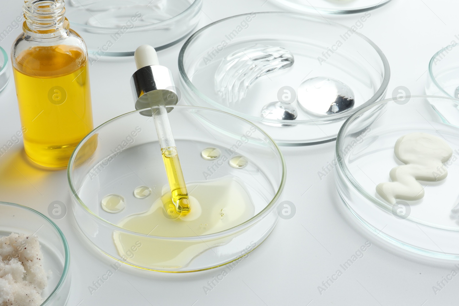 Photo of Petri dishes with different cosmetic products on white background, closeup