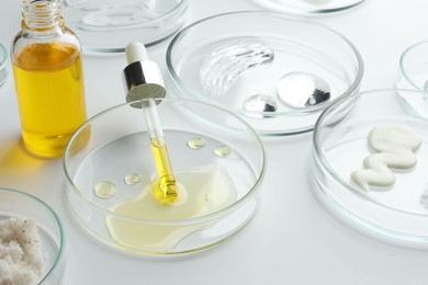 Petri dishes with different cosmetic products on white background, closeup