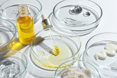 Petri dishes with different cosmetic products on white background, closeup