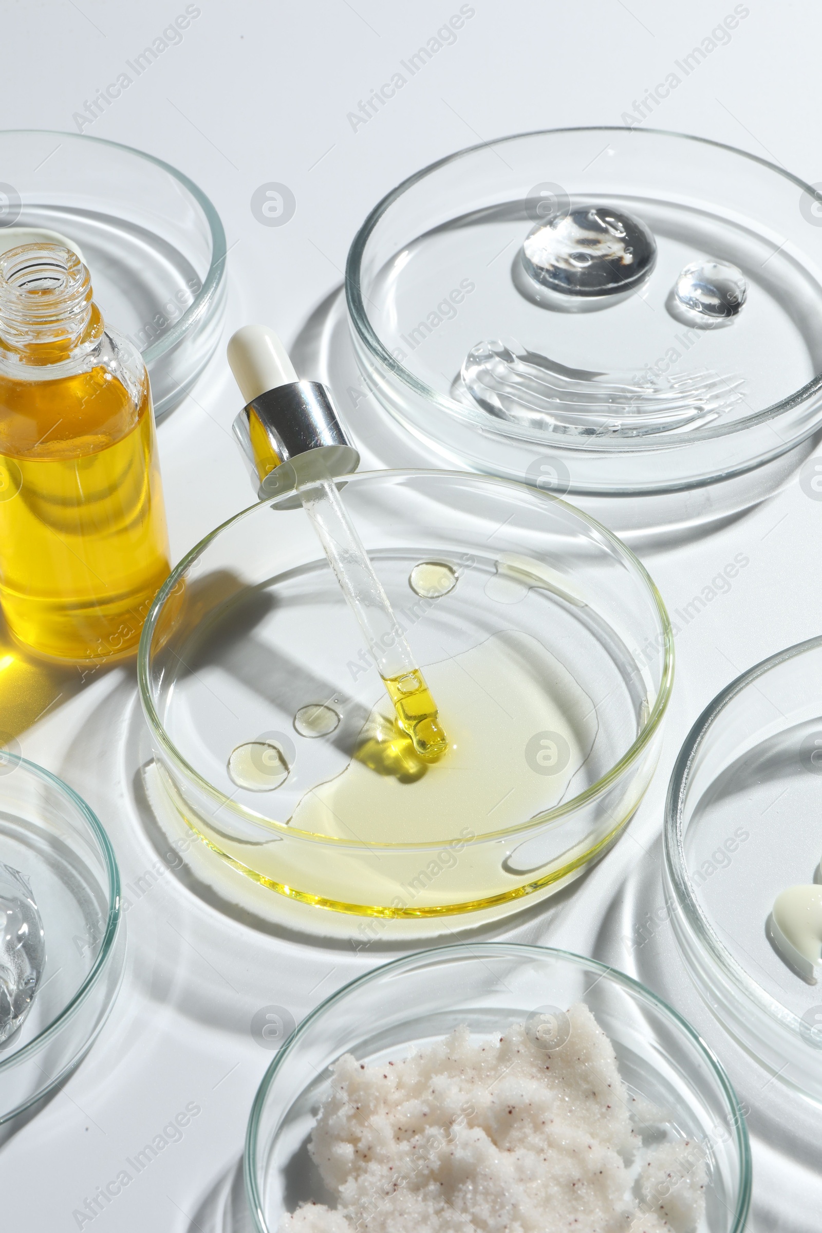 Photo of Petri dishes with different cosmetic products on white background, closeup