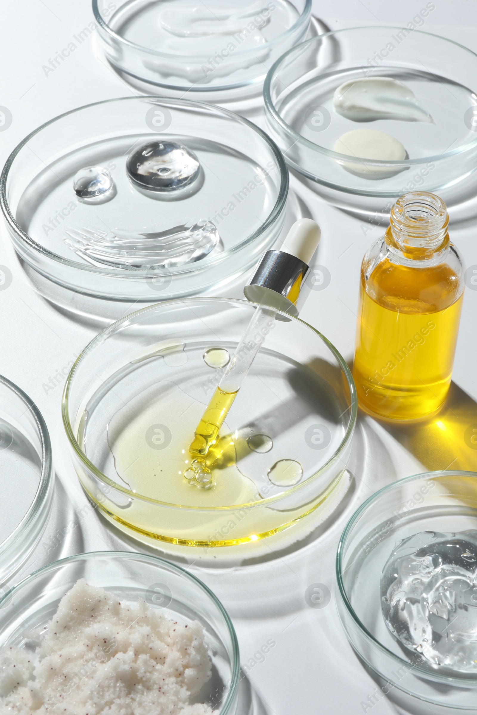 Photo of Petri dishes with different cosmetic products on white background, closeup