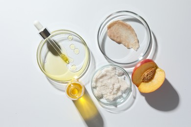 Petri dishes with different cosmetic products and peach on white background, flat lay