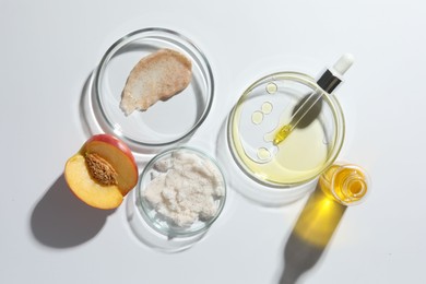 Photo of Petri dishes with different cosmetic products and peach on white background, flat lay