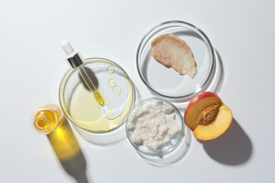 Petri dishes with different cosmetic products and peach on white background, flat lay