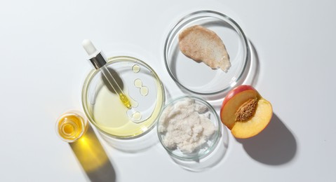 Petri dishes with different cosmetic products and peach on white background, flat lay