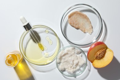 Petri dishes with different cosmetic products and peach on white background, flat lay