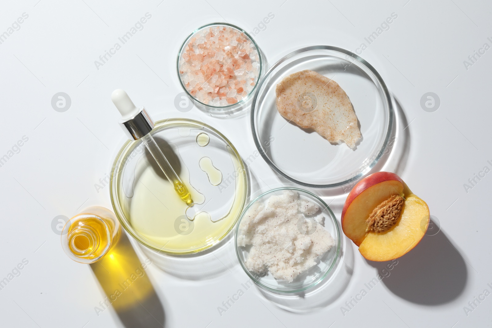 Photo of Petri dishes with different cosmetic products and peach on white background, flat lay