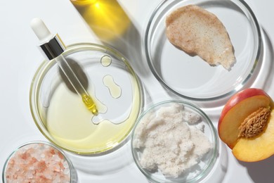 Photo of Petri dishes with different cosmetic products and peach on white background, flat lay