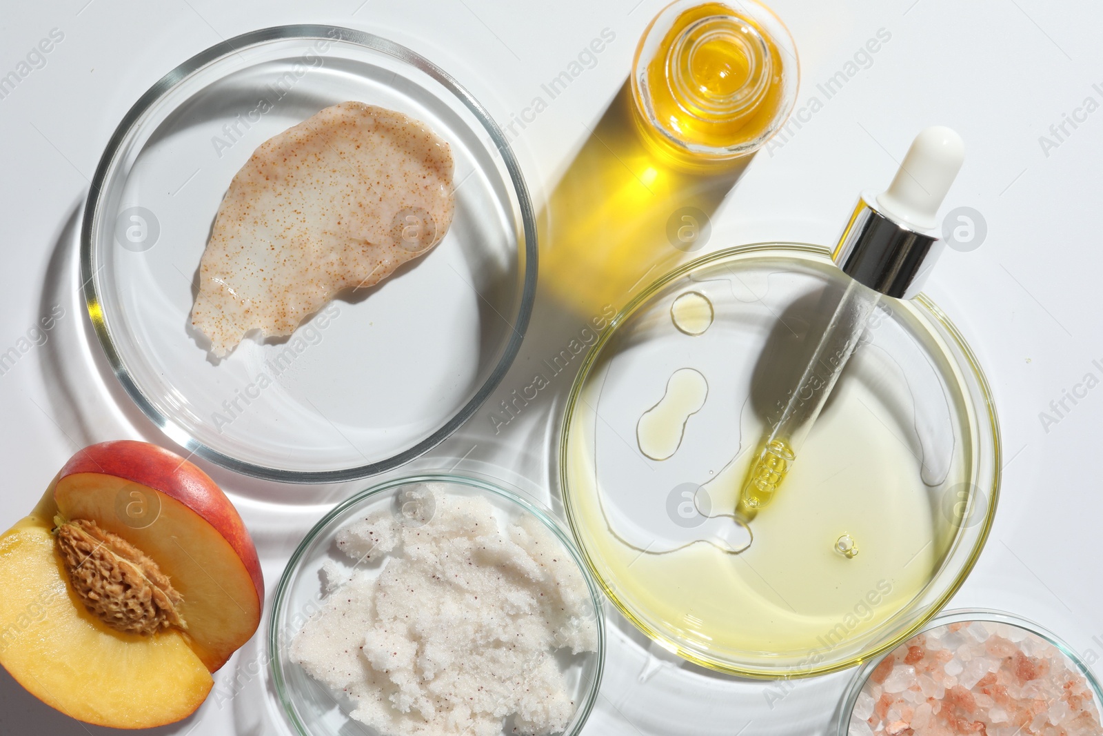 Photo of Petri dishes with different cosmetic products and peach on white background, flat lay