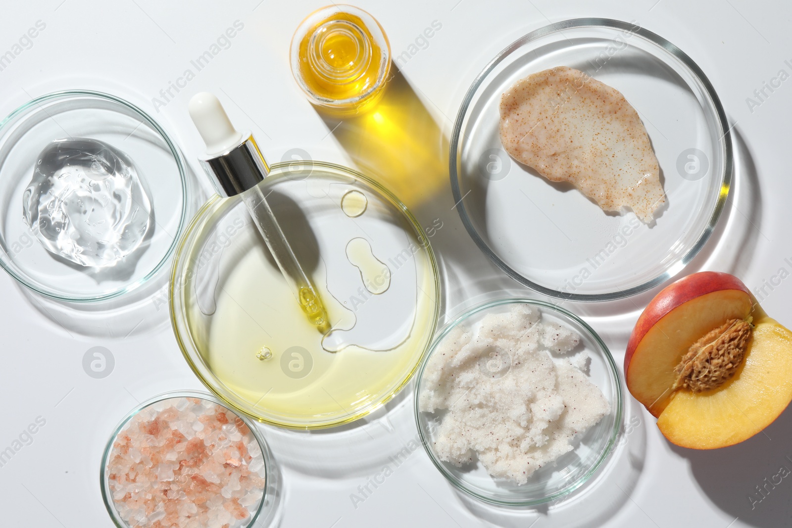 Photo of Petri dishes with different cosmetic products and peach on white background, flat lay