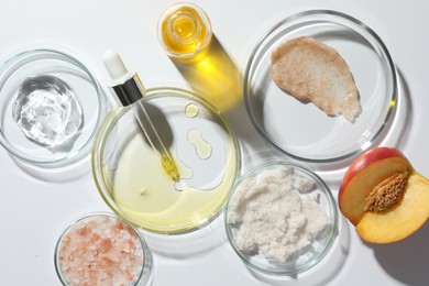 Petri dishes with different cosmetic products and peach on white background, flat lay