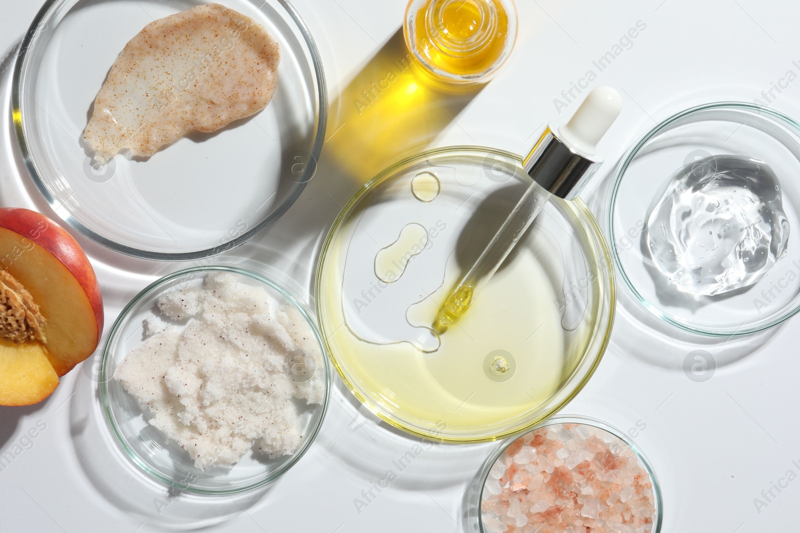 Photo of Petri dishes with different cosmetic products and peach on white background, flat lay