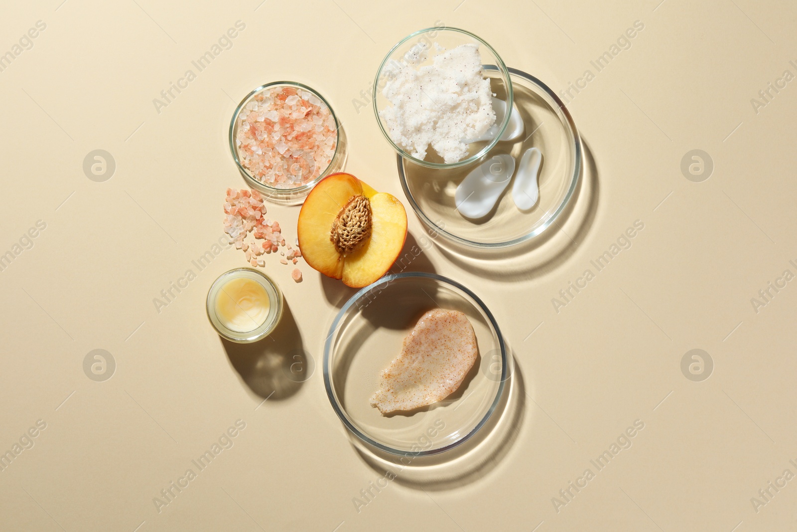 Photo of Petri dishes with different cosmetic products and peach on beige background, flat lay