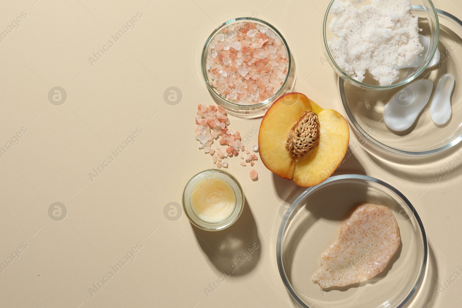 Photo of Petri dishes with different cosmetic products and peach on beige background, flat lay. Space for text