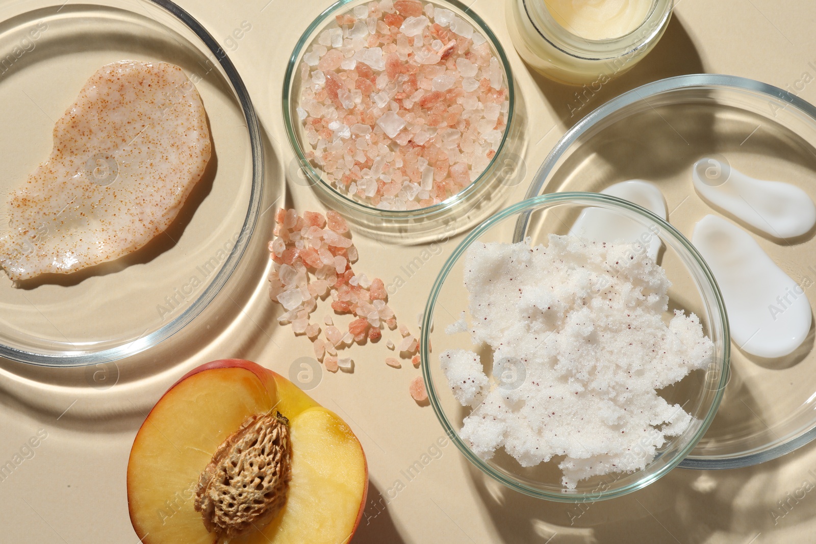 Photo of Petri dishes with different cosmetic products and peach on beige background, flat lay