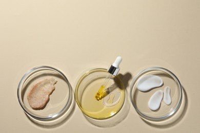 Petri dishes with different cosmetic products on beige background, flat lay. Space for text