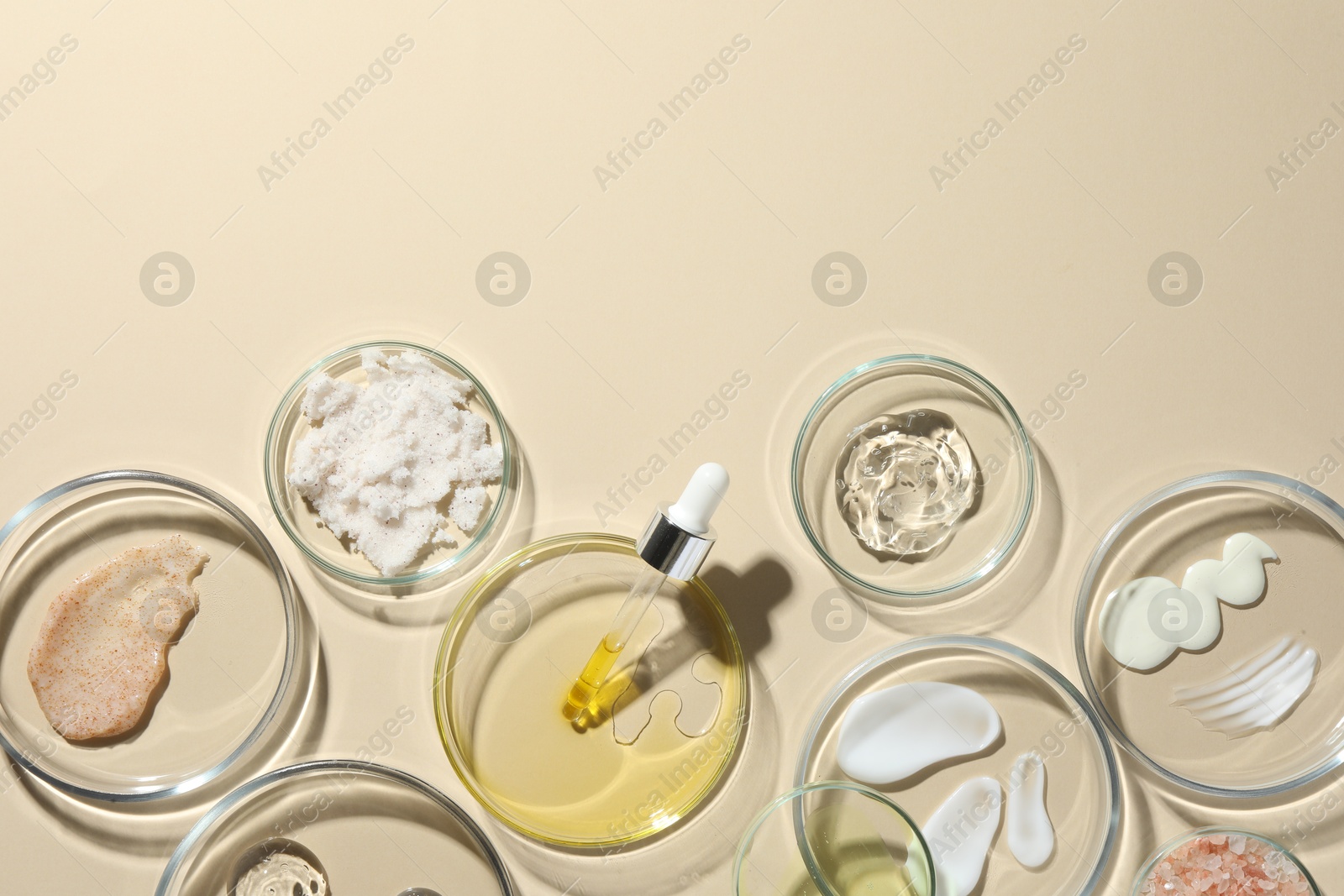 Photo of Petri dishes with different cosmetic products on beige background, flat lay. Space for text