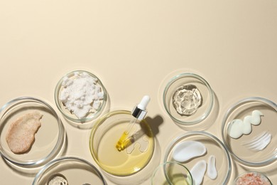 Petri dishes with different cosmetic products on beige background, flat lay. Space for text