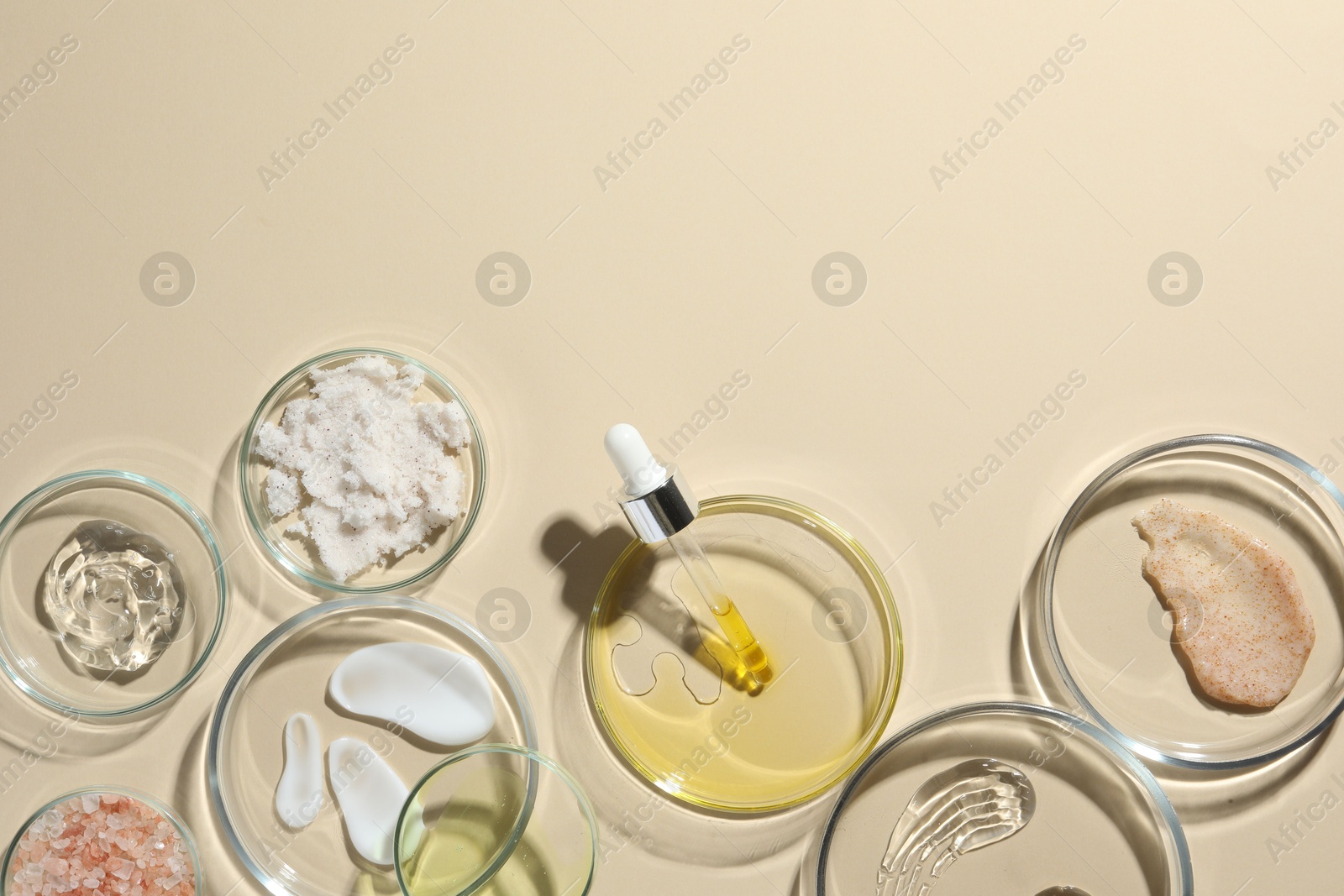 Photo of Petri dishes with different cosmetic products on beige background, flat lay. Space for text