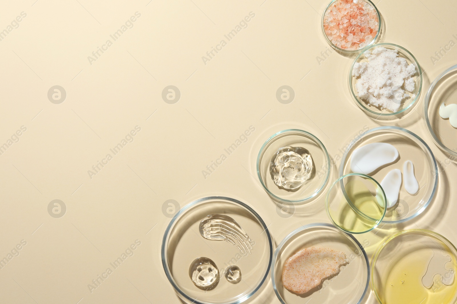 Photo of Petri dishes with different cosmetic products on beige background, flat lay. Space for text