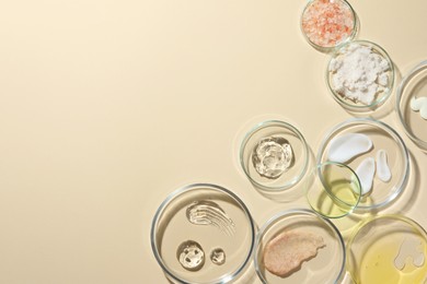 Petri dishes with different cosmetic products on beige background, flat lay. Space for text