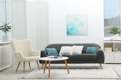 Photo of Comfortable sofa, armchair, coffee table and folding screen in living room