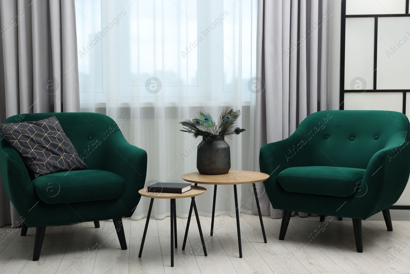 Photo of Comfortable armchairs, coffee table and folding screen near window in living room