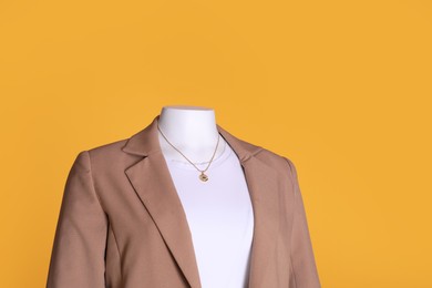 Photo of Female mannequin dressed in white t-shirt with necklace and stylish jacket on orange background