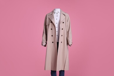 Photo of Female mannequin dressed in stylish stretch coat, jeans and shirt on pink background