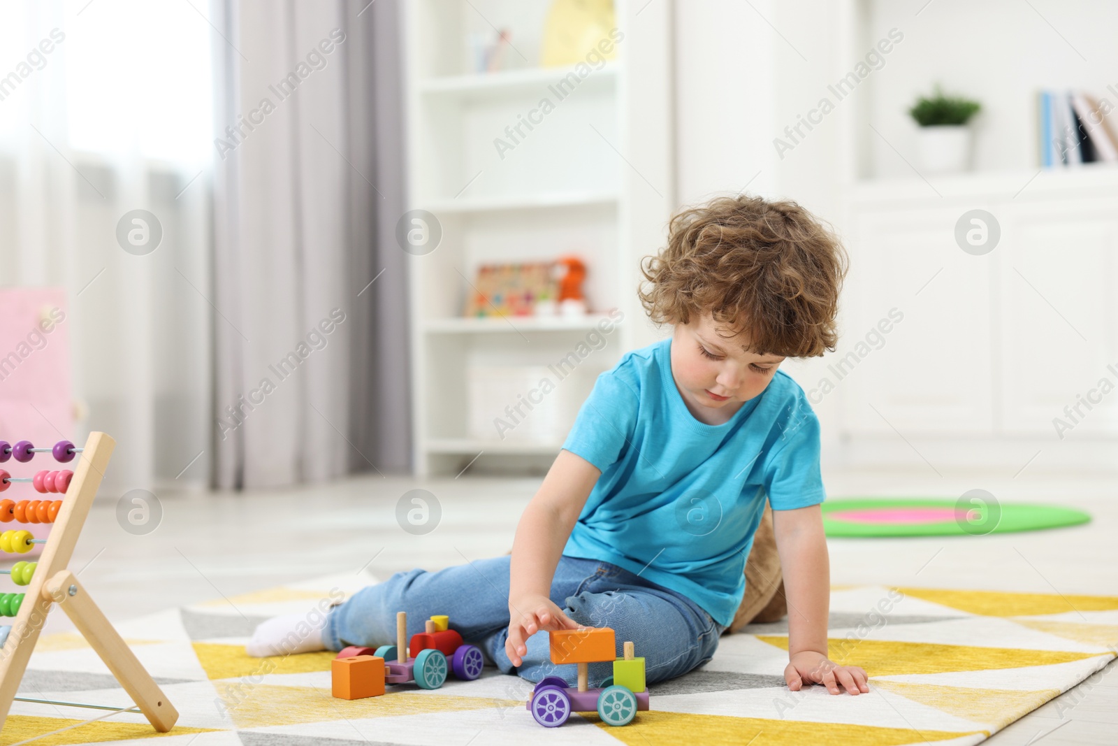 Photo of Cute little boy playing with toy cars on floor in kindergarten