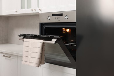 Photo of Open electric oven with towel in kitchen. Cooking appliance